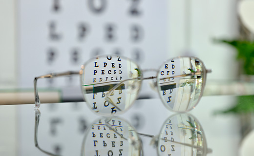 Glasses with Snellen eye chart in the backgroung